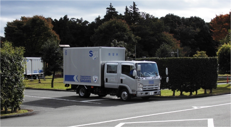 灰色の佐川急便教習トラック。荷台にSGHのロゴ、TRANSPORT! COMMUNICATION SAGAWAの文字がある。