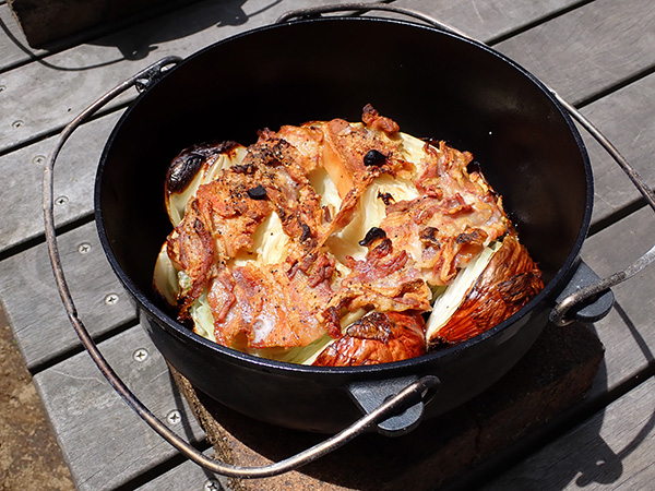 大きなキャベツと皮付きのまま焼かれた玉ねぎの上に豚肉が乗っています