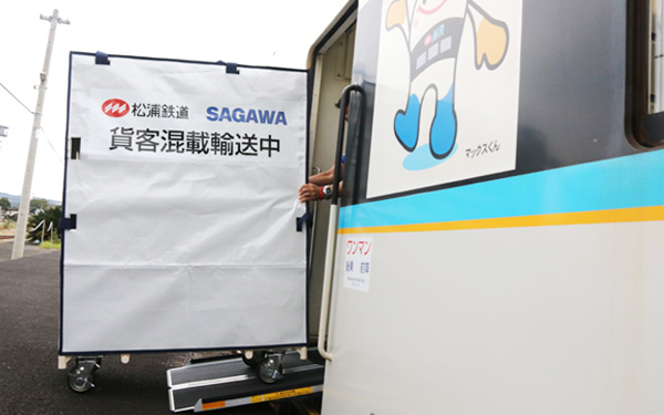 松浦鉄道SAGAWA貨客混載輸送中の台車が、マックスくんのイラストがある車両に載せられている。